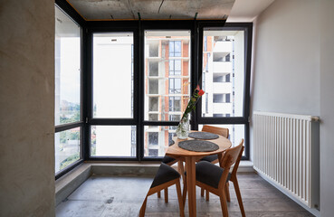 Photo collage of living room with large panoramic window before and after renovation. Old apartment with heating radiator and new renovated flat with flowers on table and elegant interior design.