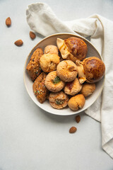 Variety of homemade Italian sweets typical for Sardinia region. Pardulas, amaretti, papassine and pizzicchi in bowl on white table.