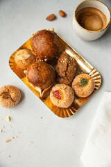 Variety of homemade Italian sweets typical for Sardinia region. Pardulas, amaretti, papassine and pizzicchi on golden plate and cup of espresso on white table.