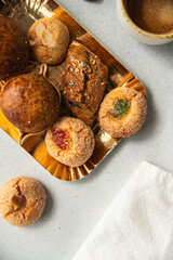 Variety of homemade Italian sweets typical for Sardinia region. Pardulas, amaretti, papassine and pizzicchi on golden plate and cup of espresso on white table.