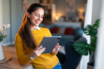 Young woman looking at tablet pc. Woman entrepreneur in business casual outfit looking at a tablet pc at home.