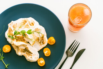 Healthy egg white breakfast with yellow cherry tomatoes and herbs on a blue plate with a glass of orange juice on a light background