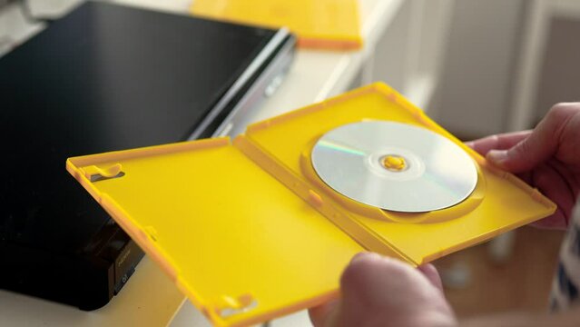 Man opens a yellow box with cd disc. Physical media concept.