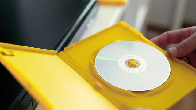 Man opens a yellow box with cd disc. Physical media concept.
