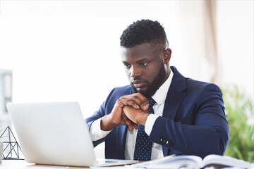 Concentrated young african american guy working with laptop in office, copy space