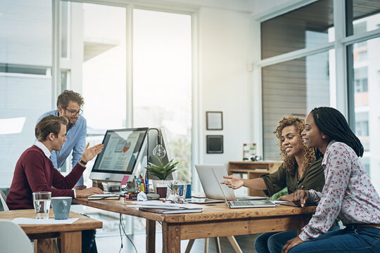 Teamwork, computer and business people at desk in coworking space for discussion, planning project or feedback. Lens flare, diversity and staff at design agency for collaboration, review or report