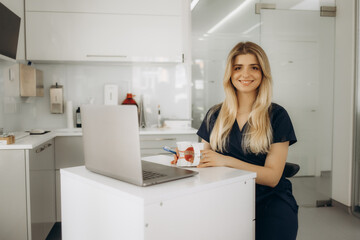 Doctor dentist sitting in the office using a laptop