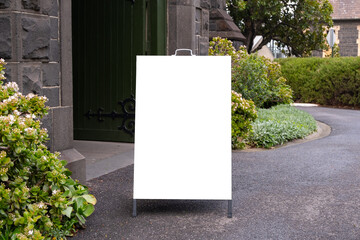 Background texture of a blank white mockup board outside a historic church building. Empty template of A-Frame standing easel sign. Copy space for design.