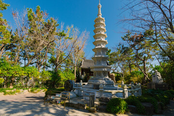 a multi-tiered stone pagoda at the Haedong Yonggungsa Temple in Korea, nestled amidst lush green...