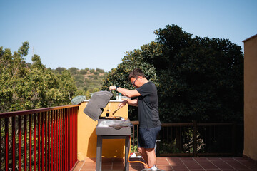 A man grilling food on a gas grill on an outdoor terrace with a scenic view