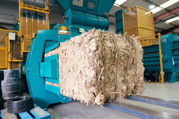 A paper recycling factory plant shredding machine, shredding waste paper into square bails, ready...
