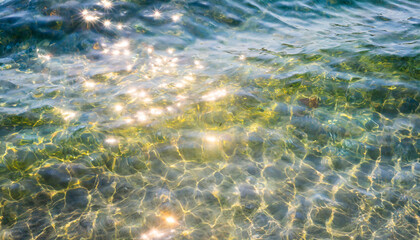 Obraz premium water waves of the sea and ocean with glare and rays of the sun, summer wallpaper for the presentation of recreation and vacation