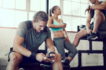 Man, fitness and typing with phone at gym for workout schedule, routine or browsing tips. Active male person scrolling on mobile smartphone for online tutorial, sports or exercise at health club