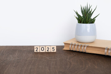 Wooden letters spelling date 2025, notebook, daily planner on vintage wooden table, potted indoor...