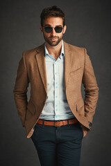 Obraz premium Confident, portrait and man for fashion in studio with stylish, trendy and smart luxury clothes as Professor. Pride, male person and designer glasses, elegant and hands in pocket on grey background