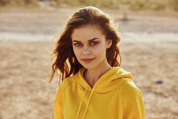 Portrait of a woman in a yellow hoodie standing confidently in the desert landscape