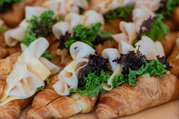 Ham cheese with fresh vegetables croissant sandwich served on wooden board.