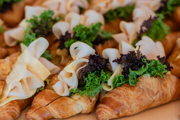 Ham cheese with fresh vegetables croissant sandwich served on wooden board.