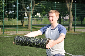 A young man in sportswear engages in a workout, using a sport tool for physical exercises on a...