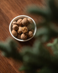 Bowl of walnuts on wooden table. handful of unshelled nuts. Cracked nut in shell. Healthy nutrients. Blurred green plant in frame. Top view. Wooden brown background. Soft focus. High quality photo