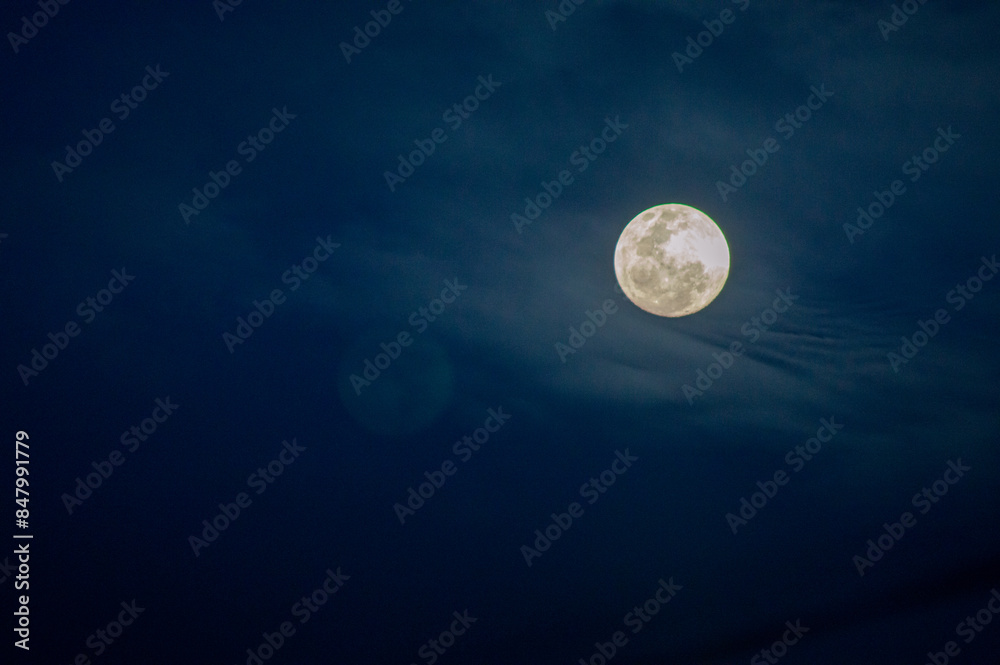 Wall mural the moon is shining brightly with clouds in the night sky.