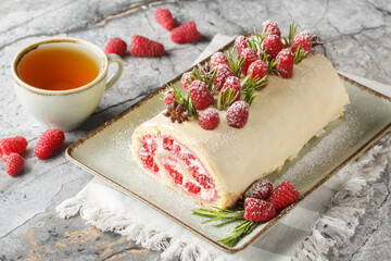 Christmas roll cake with cream, jam and fresh raspberries closeup on the plate on the table....