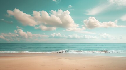 Fototapeta premium A serene beach scene with a clear blue sky and fluffy white clouds. Gentle waves lap at the sandy shore.