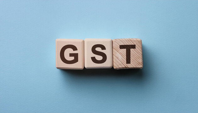 Wood blocks with abbreviation text GST - Goods and services tax. Blue backdrop. Top view