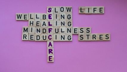 TIME LAPSE of Top view of SELFCARE word on pink background. Minimalism creative crossword puzzle concept. Message of text Slow life wellbeing healing mindfulness reducing stress mental health skincare