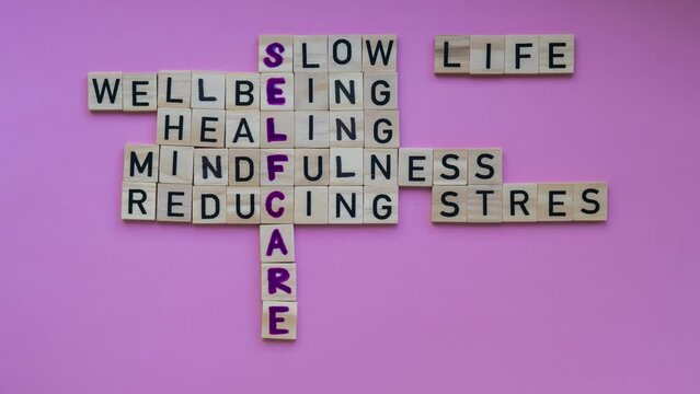 TIME LAPSE of Top view of SELFCARE word on pink background. Minimalism creative crossword puzzle concept. Message of text Slow life wellbeing healing mindfulness reducing stress mental health skincare