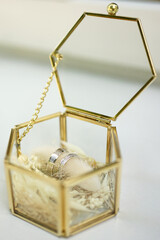 Two white gold wedding rings in a glass box.