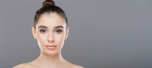 A close-up of a woman face featuring a neatly done bun in the center of her hair. Her features are visible, and the focus is on the hairstyle, panorama with copy space