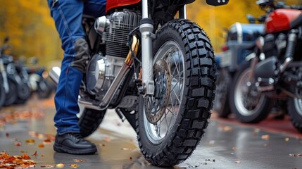 Naklejka premium A close-up shot focusing on the front wheel of a motorcycle and the rider's legs clad in jeans and boots