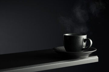 Black cup of coffee on a black background.