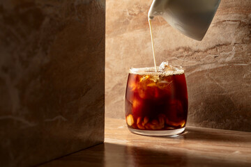 Iced coffee with cream on a beige ceramic table.