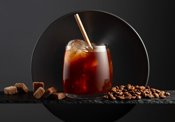 Black coffee with ice on a black background.