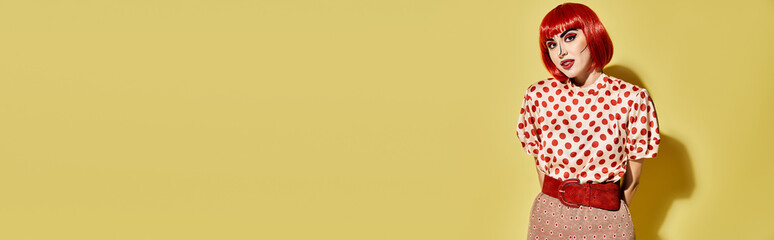 A vibrant redhead with pop art makeup dons a polka dot shirt, embodying a comic book character on a bright yellow backdrop.