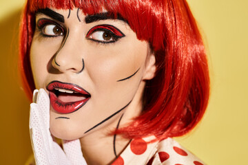 Fototapeta premium Close-up view of a pretty redhead woman with creative pop art makeup and polka dot blouse on a yellow background.