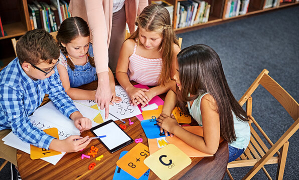Children, teacher and tablet for education with group, mockup space and blank screen in classroom. People, above and learning with books, maths and point at touchscreen for development at school