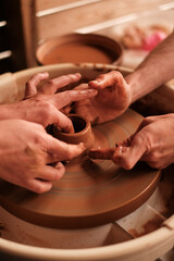 Potter teaching woman to craft ceramic jug on a pottery wheel