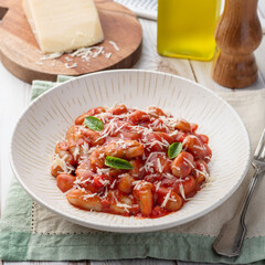 Italian pasta gnocchi on a plate with tomato sauce, basil and parmesan cheese