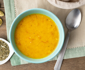 Pumpkin and jerked beef soup in a bowl with bread slices and seasoning over wooden table