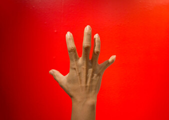 Communicate signs or symbols using sign language on a bright red background.