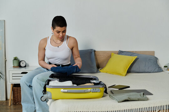 A young woman with short hair sits on a bed, packing her luggage, preparing for an upcoming vacation or trip.