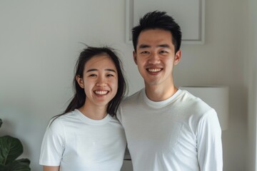 Obraz premium Portrait of a content asian couple in their 20s showing off a lightweight base layer isolated in bare monochromatic room