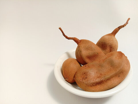 Tamarindus indica or tamarind is a sour-tasting fruit with a white background.
