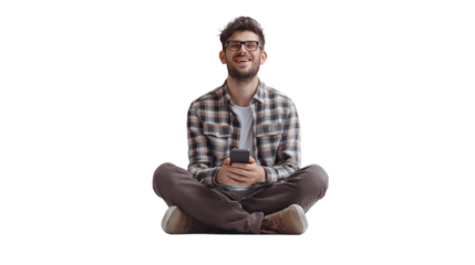 Engrossed in his smartphone, a man sits on the floor against a transparent backdrop, exuding joy.