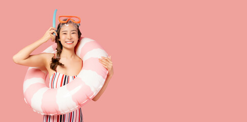 A cheerful woman wearing a striped swimsuit and snorkel gear, holding a pink and white inflatable swim ring against a pink background, radiating summer fun and vacation vibes.







