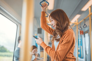 Happy young Asian woman passenger smile and using smart mobile phone in subway train station, lifestyle, transportation.