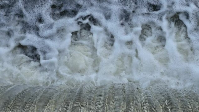 Water falls from the dam. Waterfall, top view. Streams of water. Water foam.